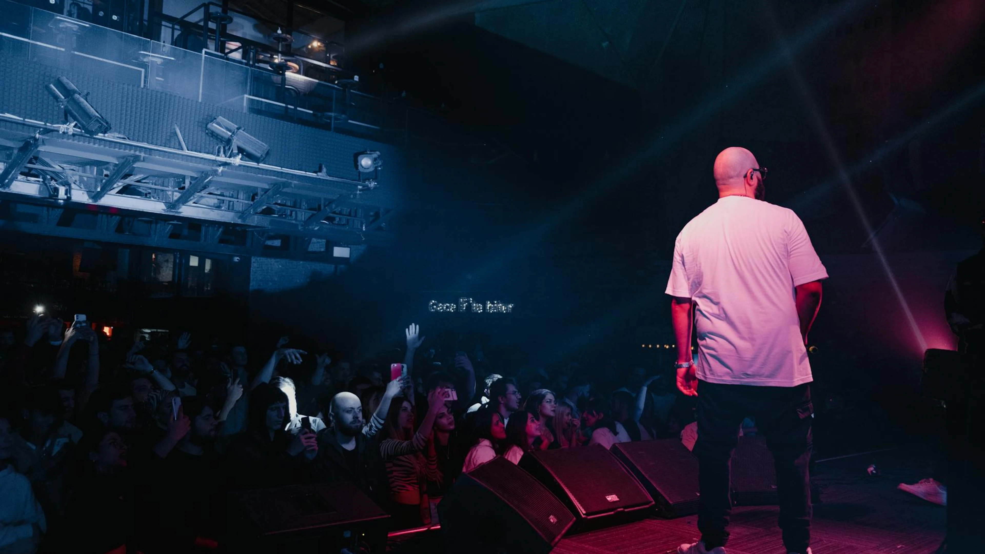 Rapper performing live on stage with vibrant lighting and engaged audience in a - free 4K Ultra HD music wallpaper for desktop