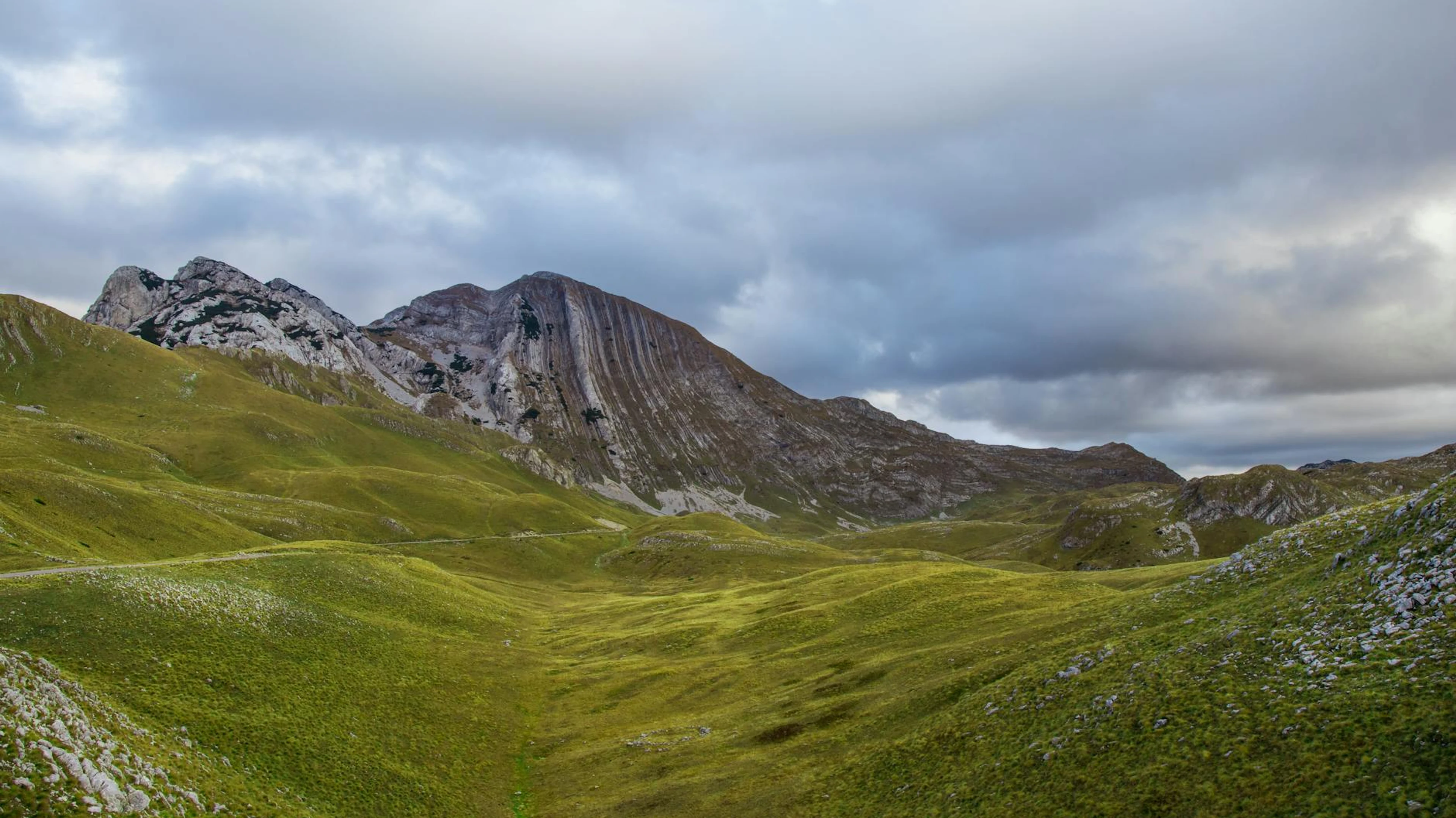Beautiful view of a grassy mountain landscape under a cloudy sky in Montenegro. - free 4K Ultra HD nature wallpaper for desktop