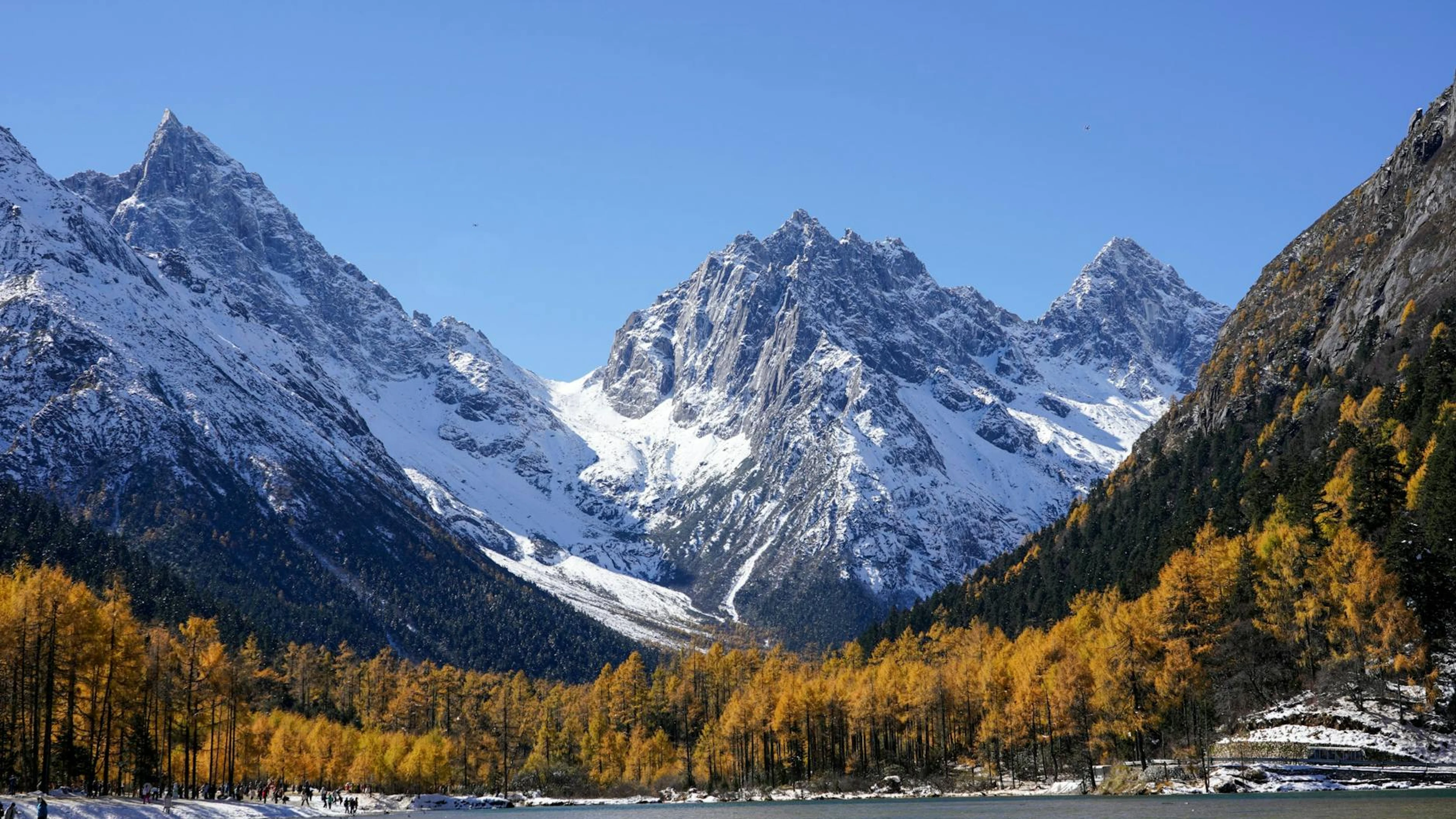 Breathtaking view of snow-capped mountains framed by autumn foliage and a serene - free 4K Ultra HD nature wallpaper for desktop