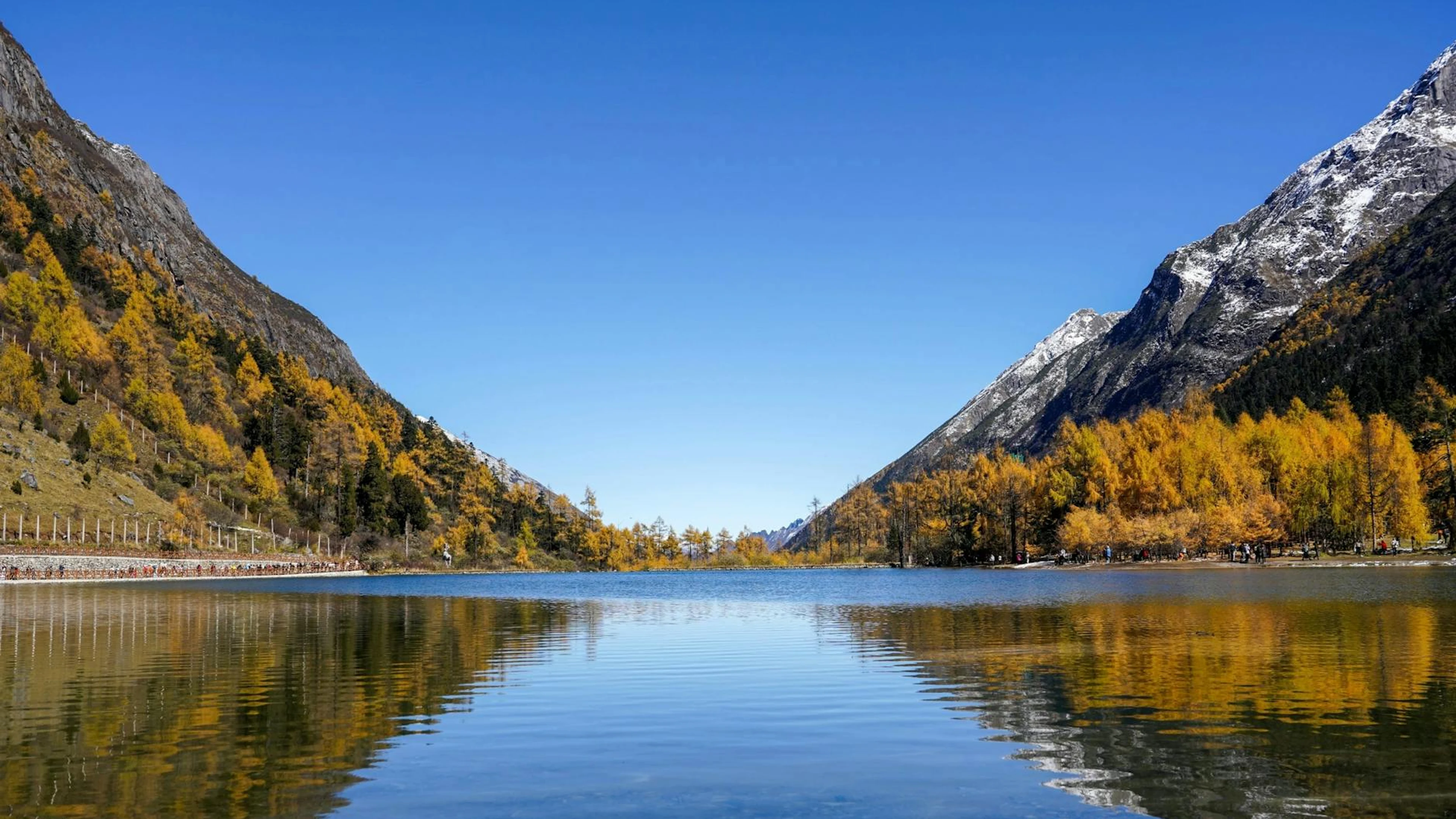 Calm alpine lake with snow-capped mountains and fall foliage reflecting on water - free 4K Ultra HD nature wallpaper for desktop
