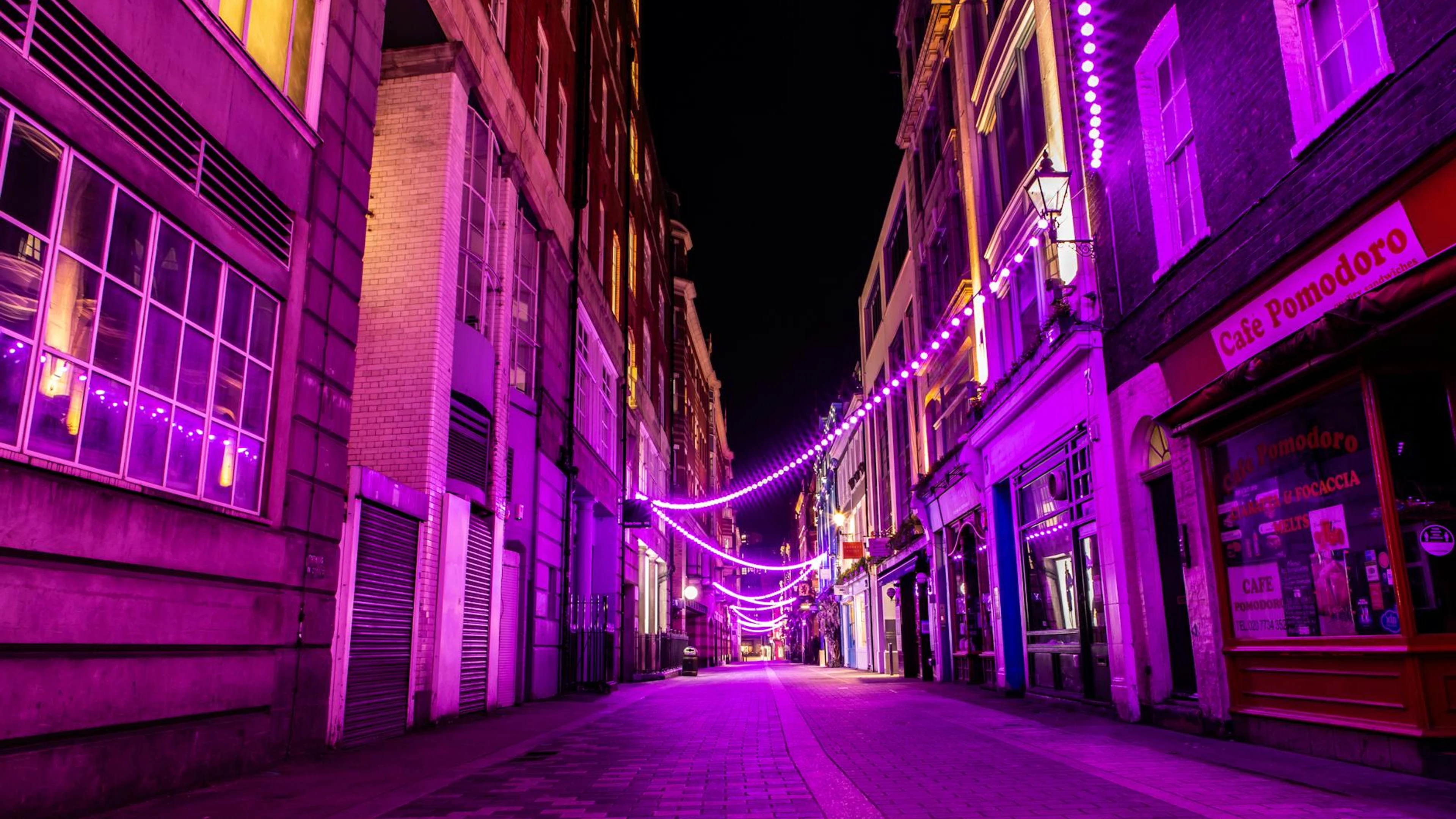 A city street illuminated by vibrant purple neon lights, creating a lively urban - free 4K Ultra HD neon wallpaper for desktop