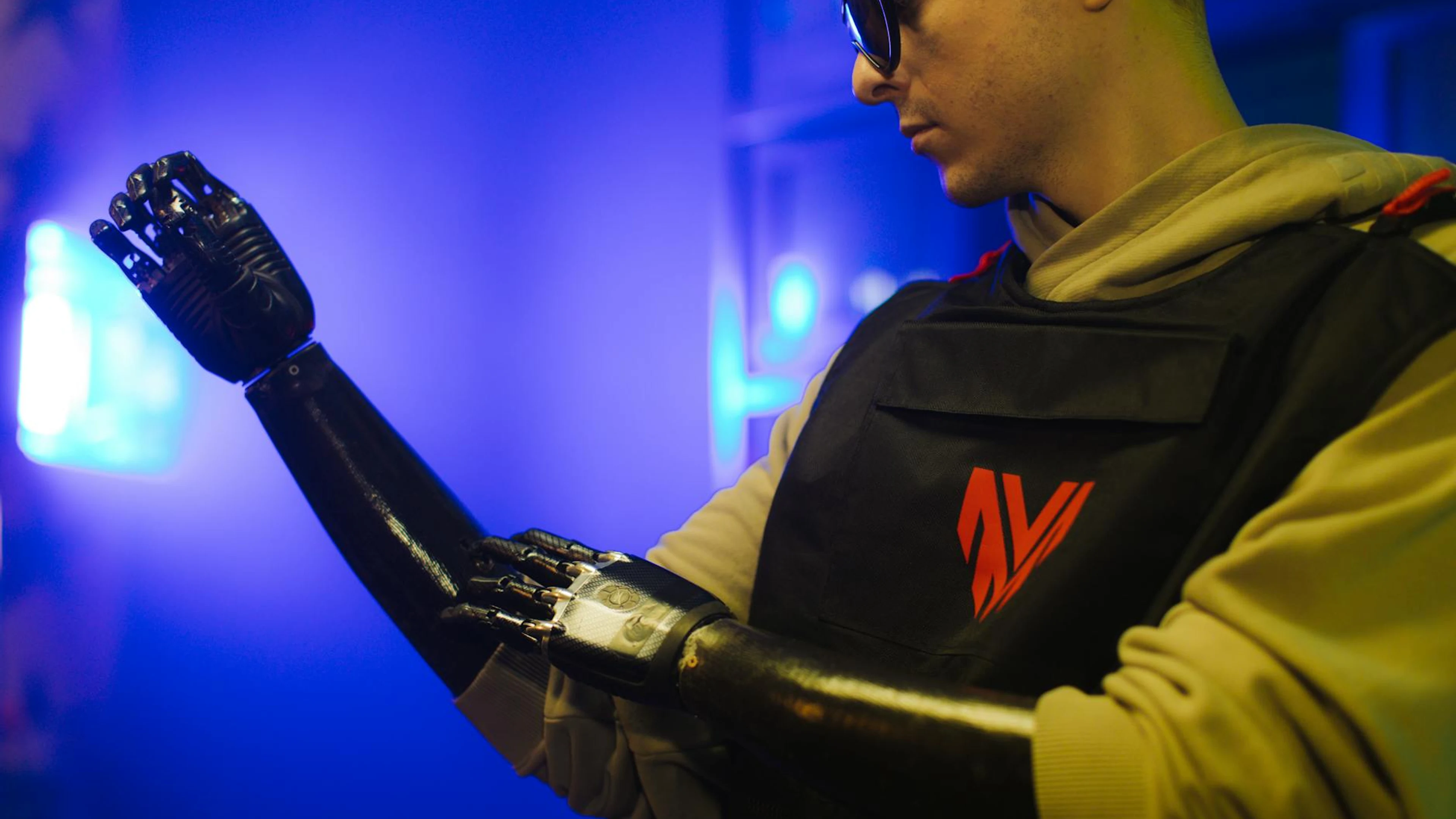 A man examines his advanced prosthetic arm in a neon-lit futuristic setting. - free 4K Ultra HD neon wallpaper for desktop