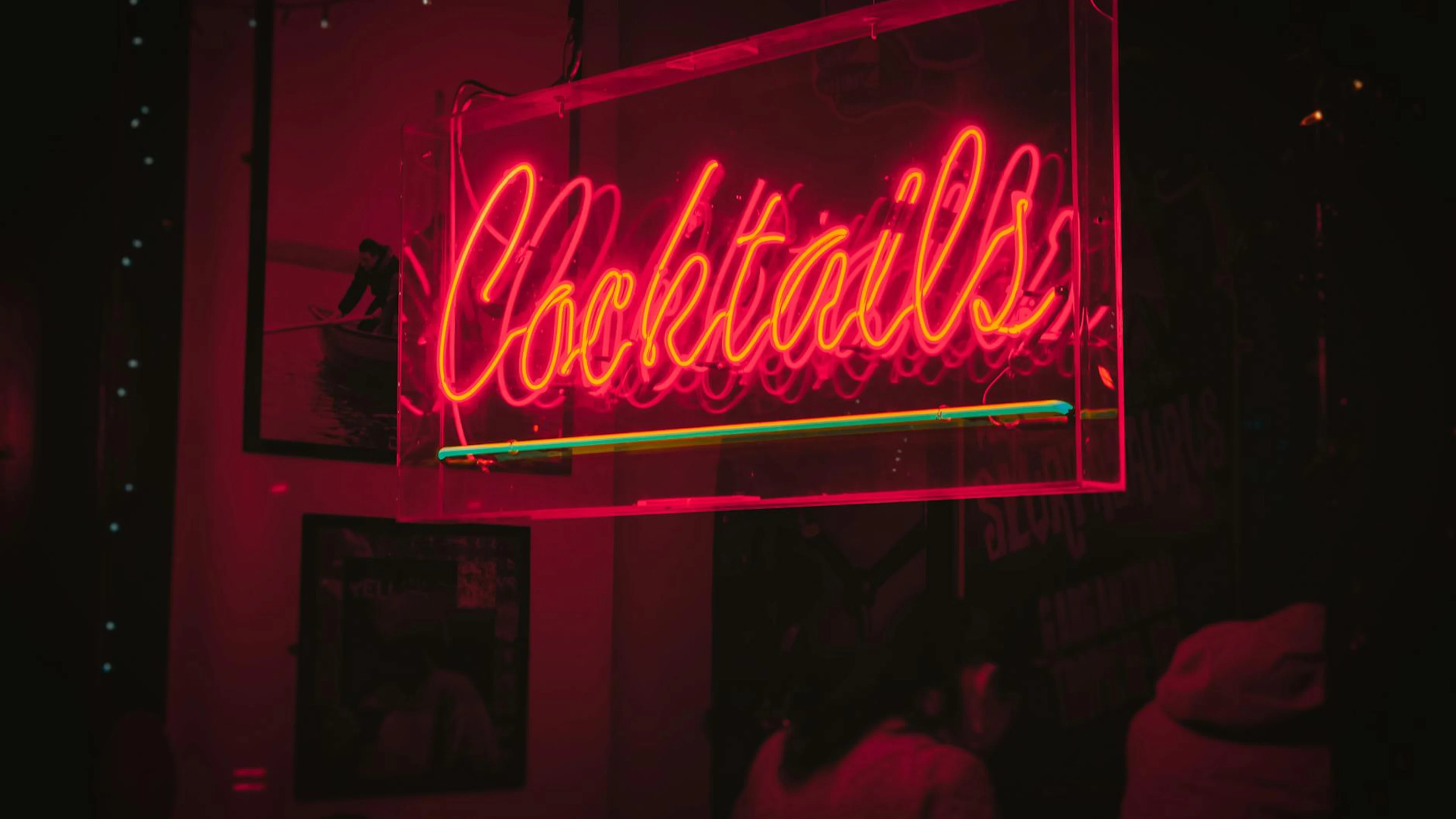 Bright neon 'Cocktails' sign glowing in a lively Dublin bar at night. - free 4K Ultra HD neon wallpaper for desktop