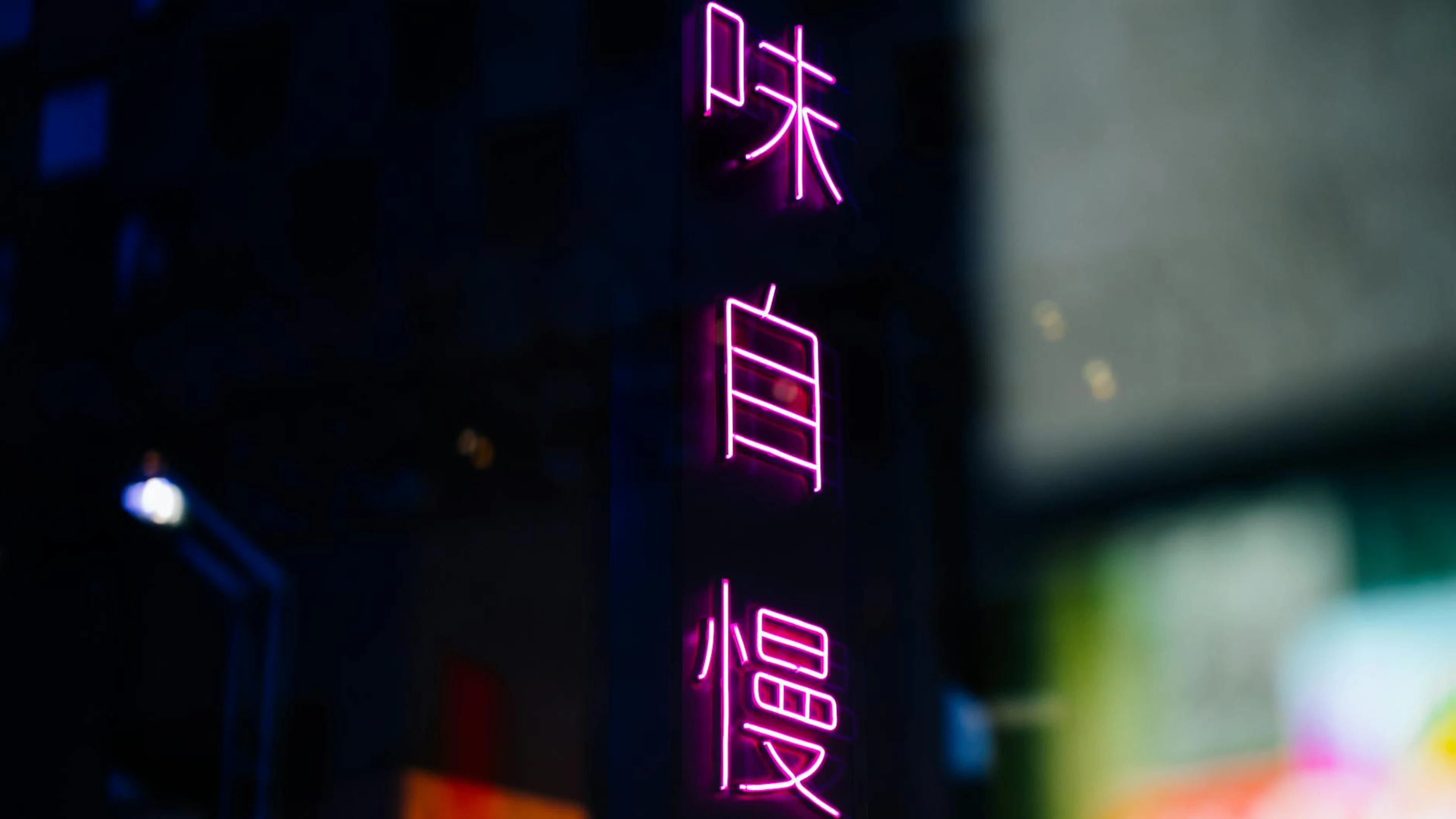 Bright pink neon Chinese characters glowing in a city night scene. - free 4K Ultra HD neon wallpaper for desktop