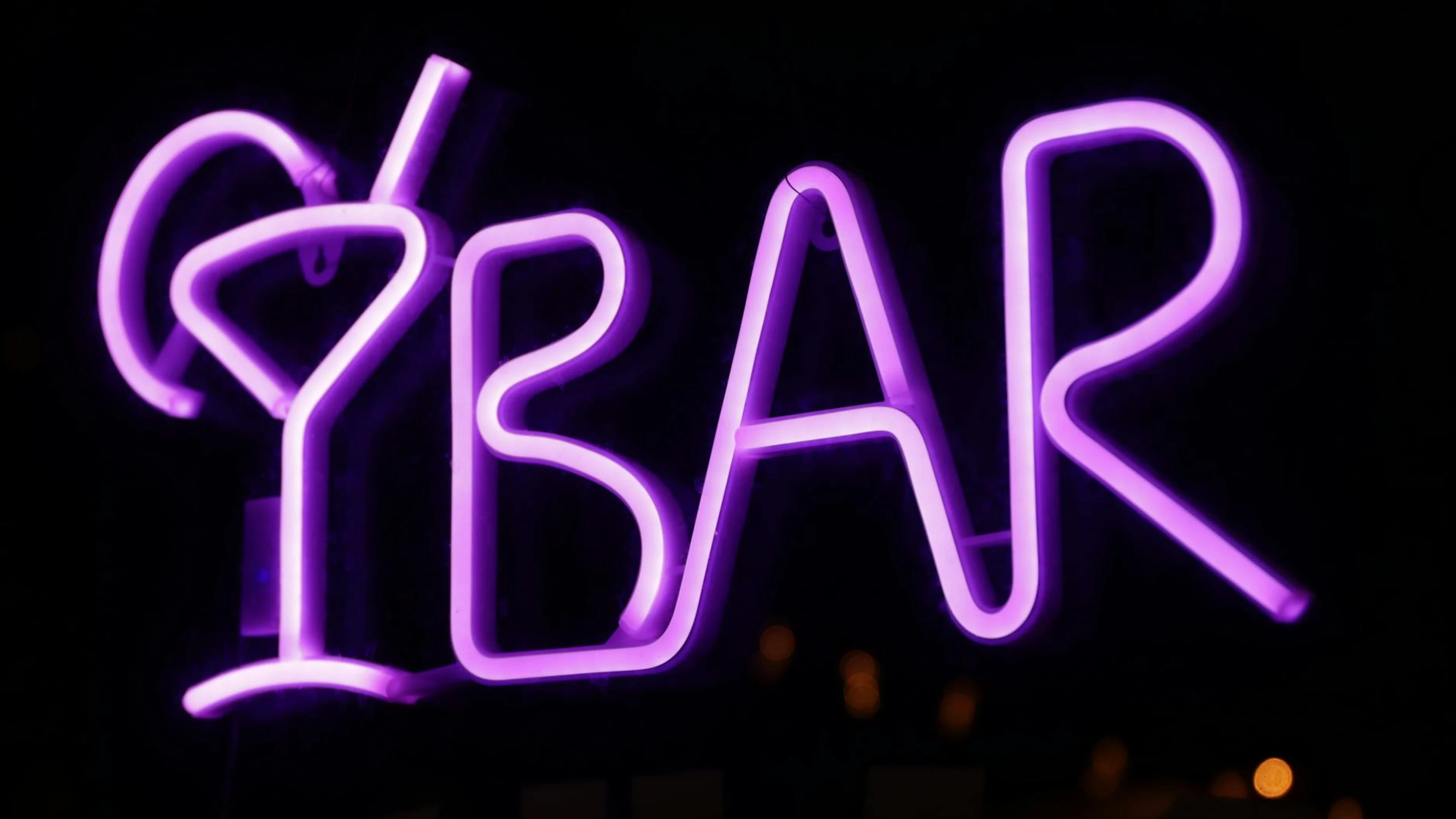 Bright purple neon sign displaying 'BAR' with a cocktail glass, set against a da - free 4K Ultra HD neon wallpaper for desktop