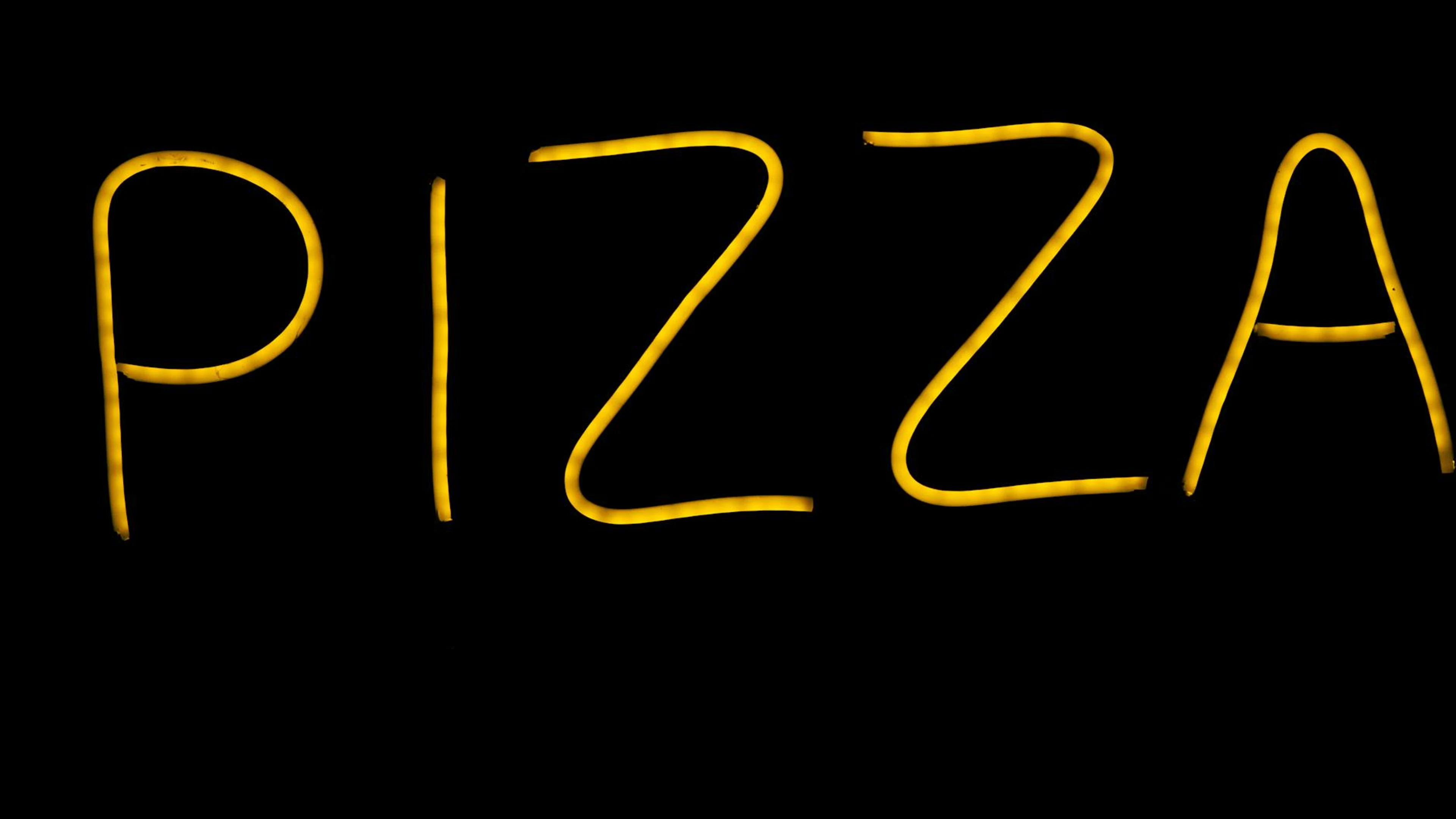 Glowing yellow neon pizza sign on a black background in Porto, Portugal. - free 4K Ultra HD neon wallpaper for desktop