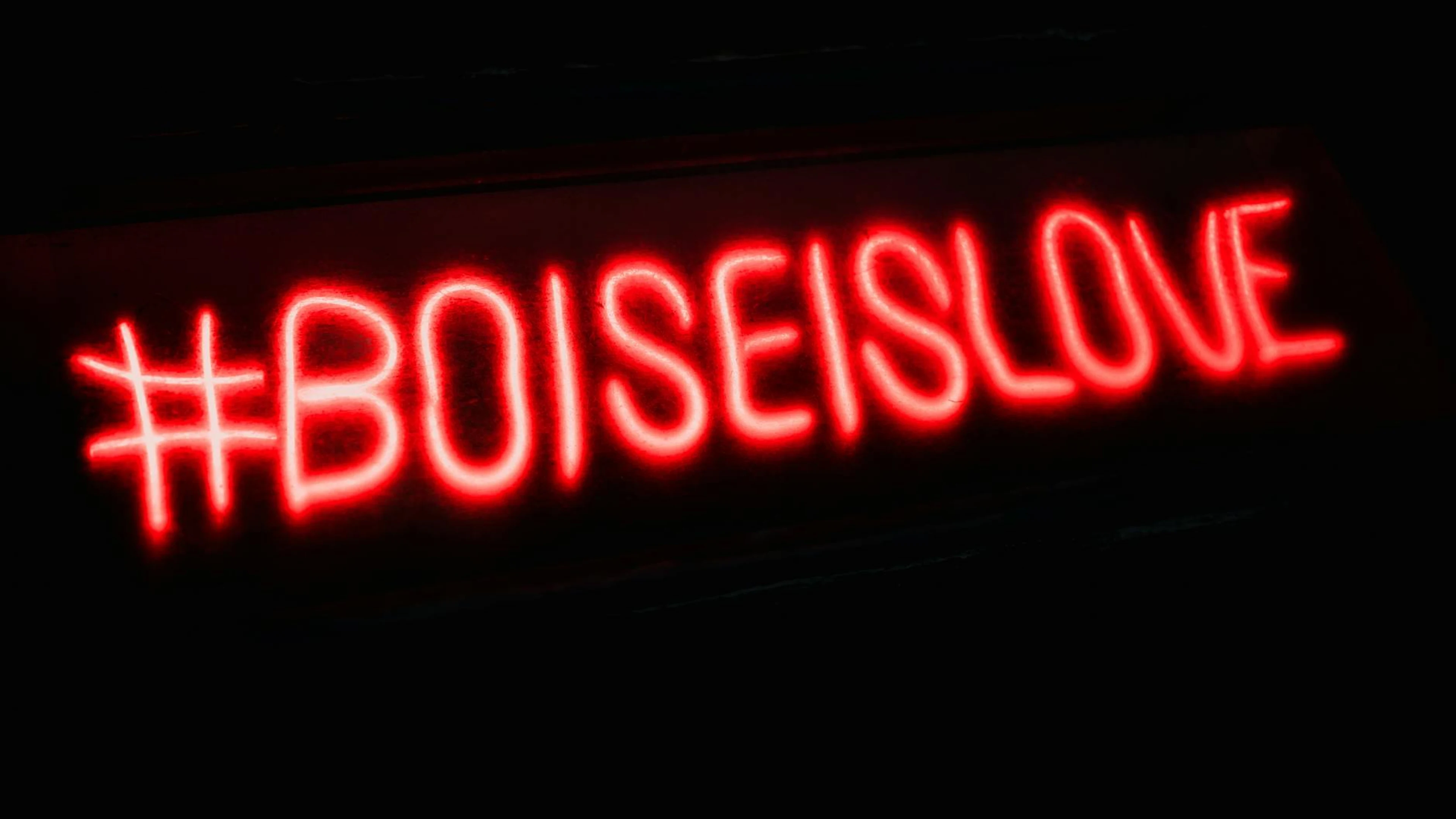Red neon sign with '#BoiseIsLove' glowing against a dark background, emphasizing - free 4K Ultra HD neon wallpaper for desktop