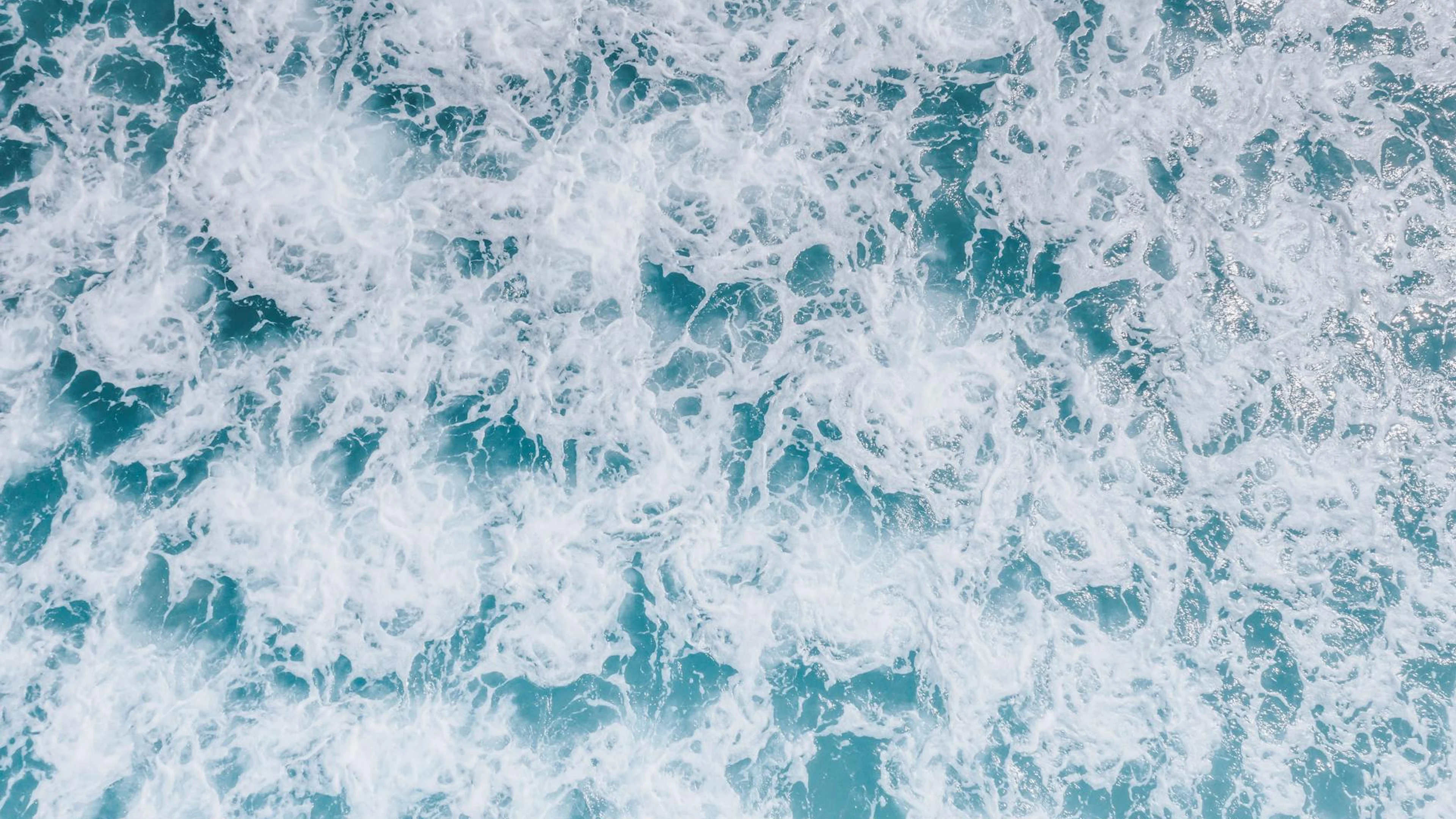 A dynamic top view of ocean waves and sea foam demonstrating nature's power and - free 4K Ultra HD ocean wallpaper for desktop