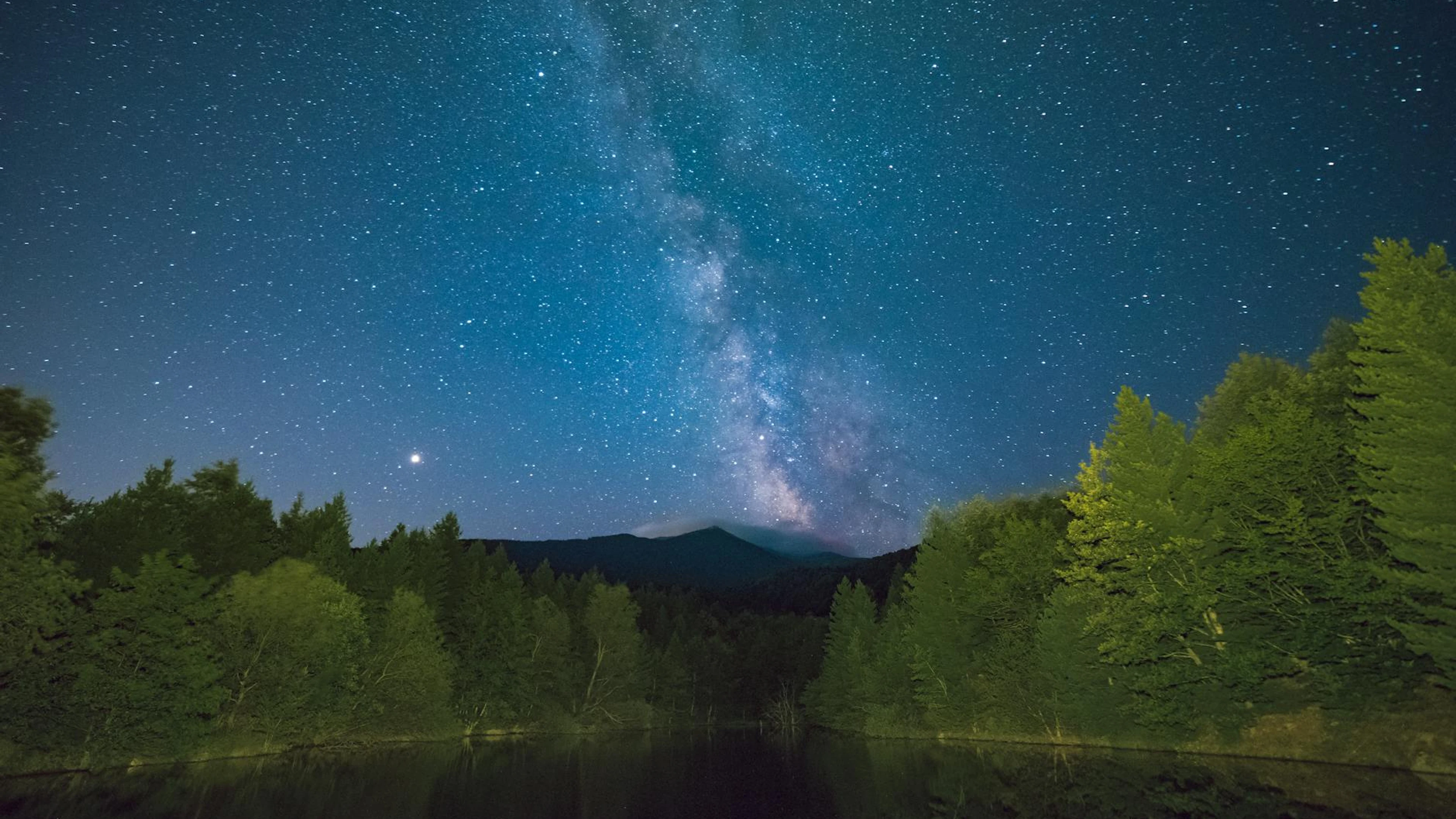 Stunning night sky with Milky Way over a serene forest lake, capturing the essen - free 4K Ultra HD space wallpaper for desktop