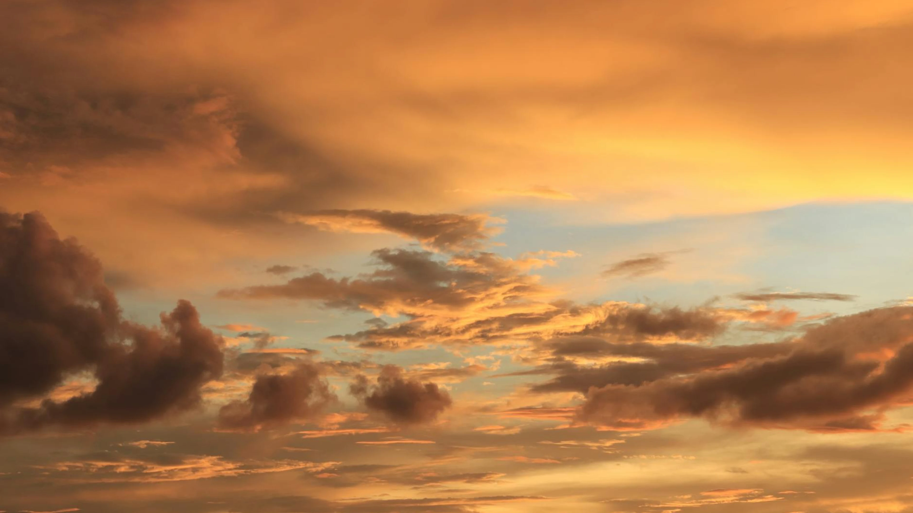 A breathtaking view of dramatic golden clouds during sunset with a serene sky. - free 4K Ultra HD sunset wallpaper for desktop