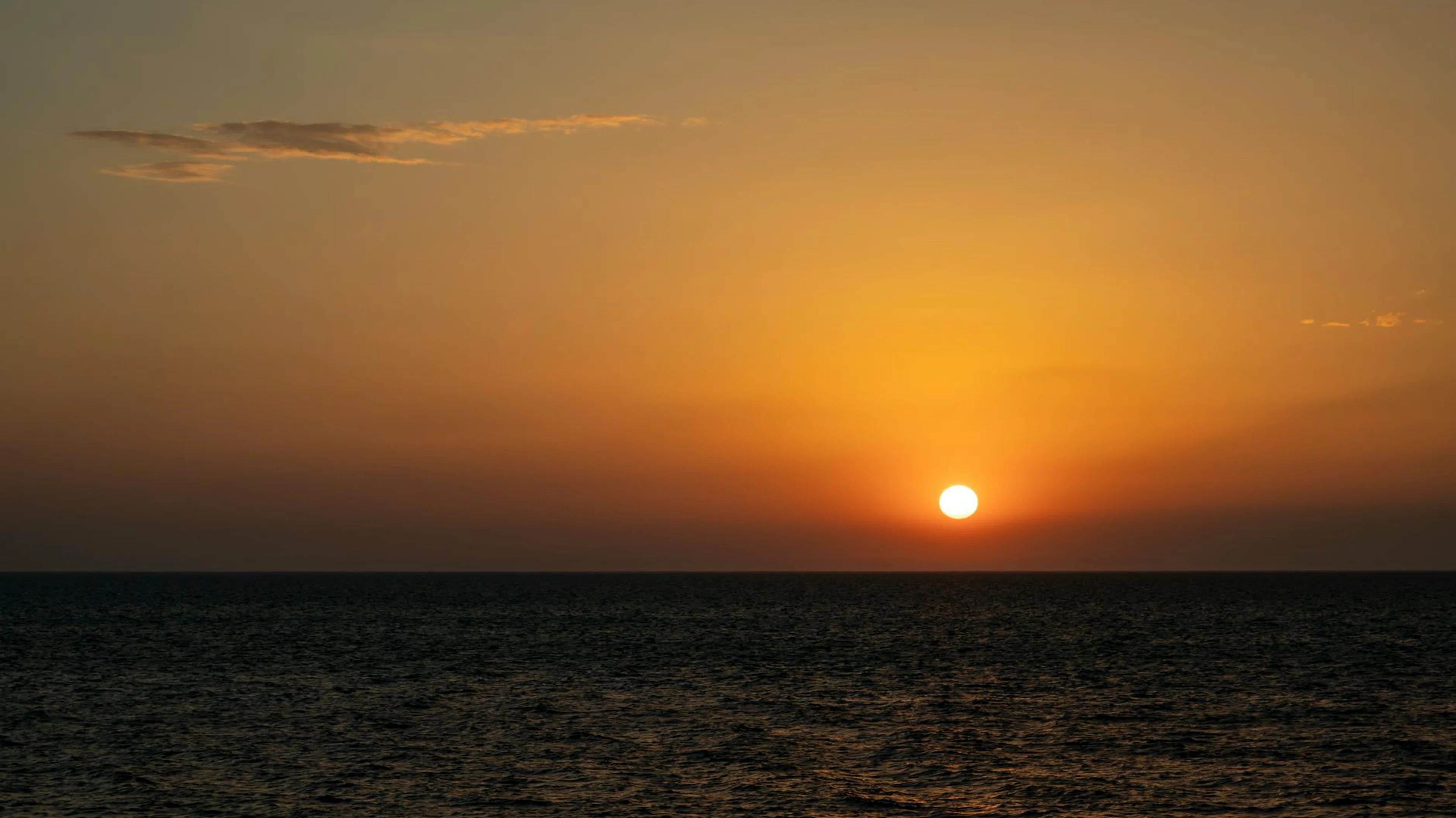 A breathtaking view of the sun setting over the ocean, creating an orange sky. - free 4K Ultra HD sunset wallpaper for desktop