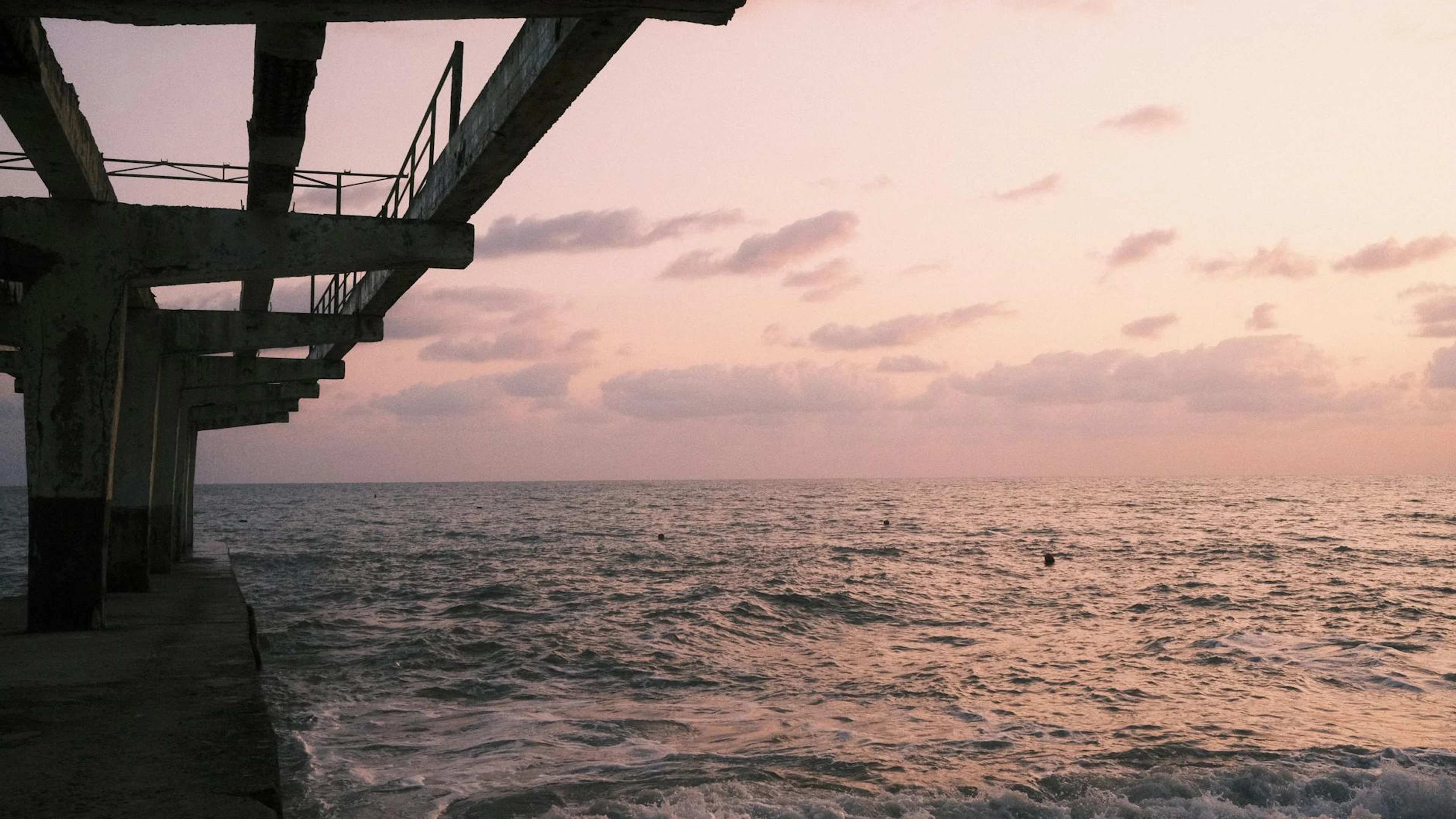 A tranquil view of a pier extending into the ocean under a serene sunset sky, pe - free 4K Ultra HD sunset wallpaper for desktop