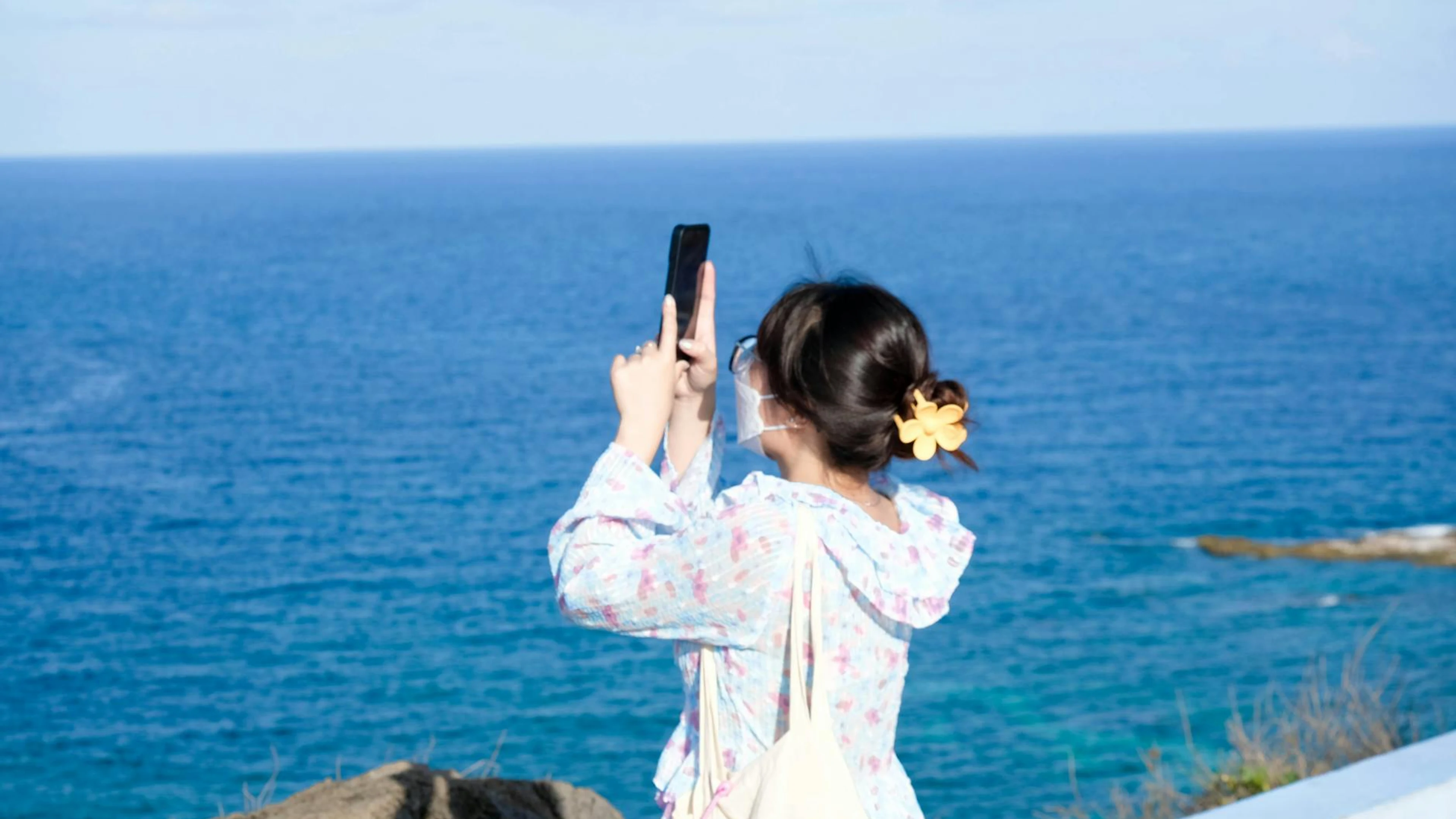 A woman taking a photo on a sunny day by the ocean with a smartphone. - free 4K Ultra HD sunset wallpaper for desktop