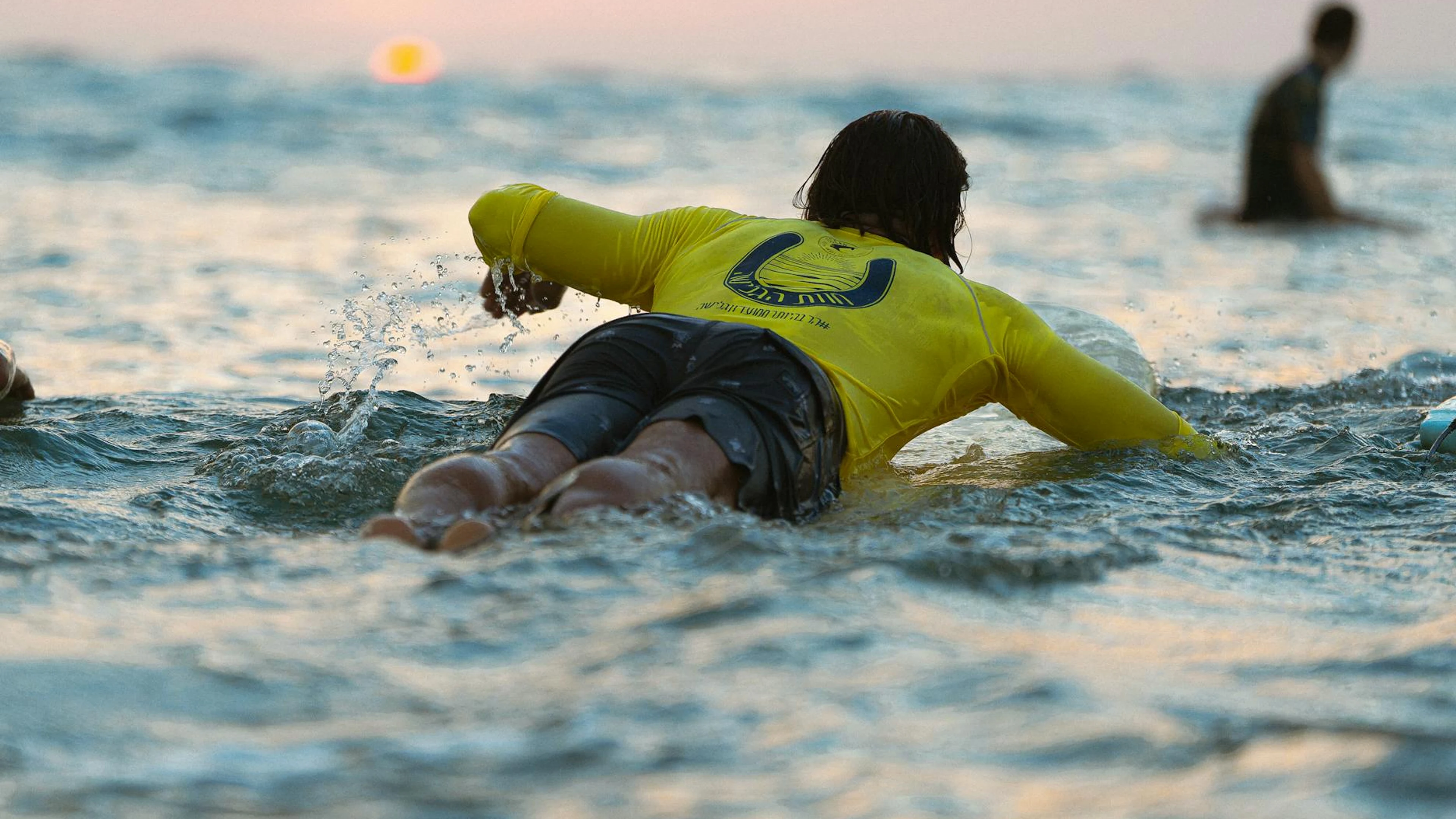 Surfer in yellow jersey paddles through ocean waves at sunset, Tel Aviv. - free 4K Ultra HD sunset wallpaper for desktop